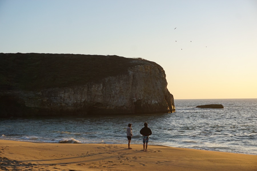 A rocky sea cliff and beach at sunset